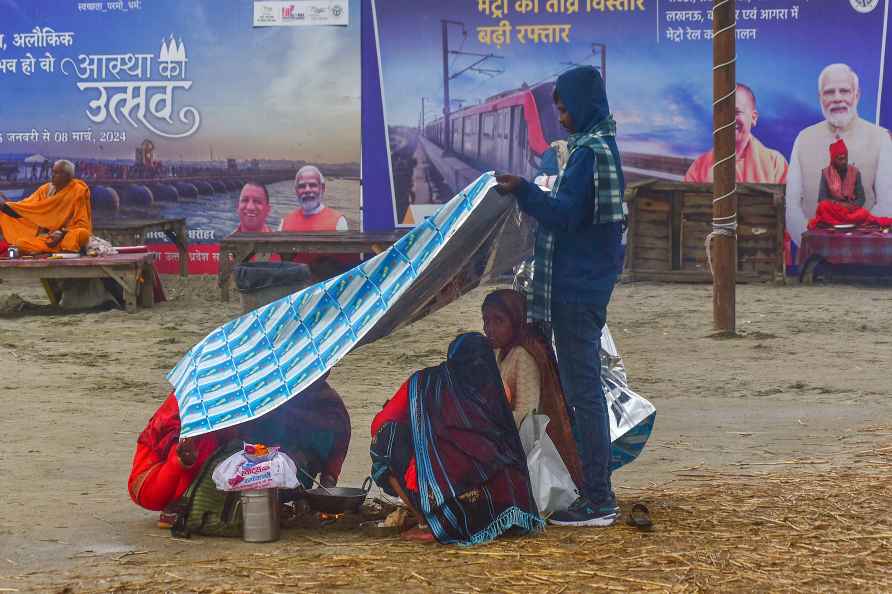 Prayagraj: Pilgrims cover themselves with a plastic sheet as it ...