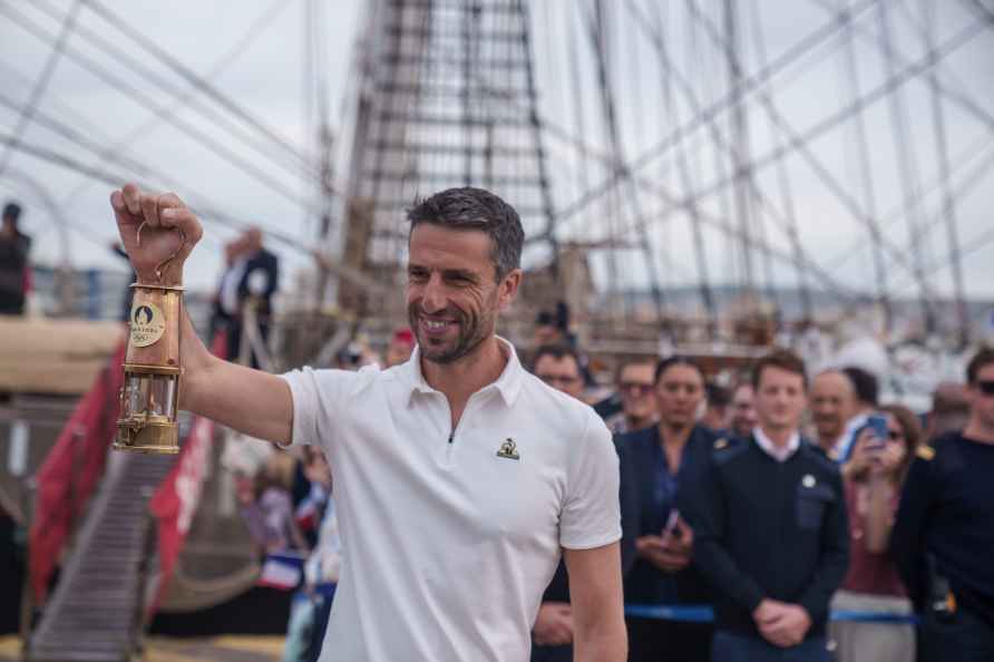 Tony Estanguet, President of Paris 2024, holds the Olympic flame...